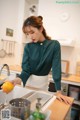 A woman in a kitchen preparing food in a sink.