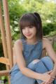 A young woman sitting on a wooden chair in a park.