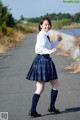 A young woman in a school uniform is walking down the street.