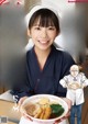 A woman holding a bowl of food in front of a poster.