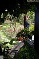 A woman standing in the middle of a lush green garden.