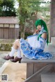 A woman with green hair sitting on a wooden bench.