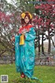 A woman in a blue kimono holding a red fan.