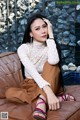 A woman sitting on top of a brown couch.