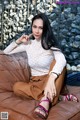 A woman sitting on top of a brown couch.