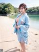 A woman in a blue kimono standing on a beach.