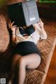 A woman laying on a couch holding a book over her head.