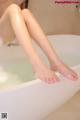 A woman sitting in a bathtub with her feet in the water.