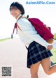 A young woman in a school uniform with a backpack.