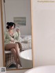 A woman sitting on a wicker chair in front of a mirror.