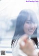 A woman with long black hair standing in front of a window.