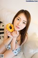 A woman sitting on a bed holding a donut in her hand.