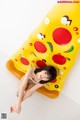 A woman in a bikini laying on an inflatable pizza.