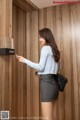 A woman standing in front of a wooden wall holding a cell phone.