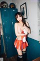 A woman in a cheerleader outfit posing in front of lockers.