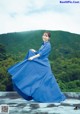 A woman in a blue dress sitting on top of a roof.