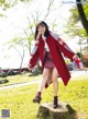 A woman in a red coat is standing on a tree stump.