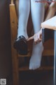 A person sitting on a chair with a pair of shoes on their feet.