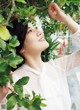 A woman in a white blouse is looking up at the sky.