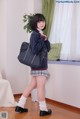 A young woman in a school uniform holding a black bag.