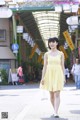 A woman in a yellow dress walking down a street.