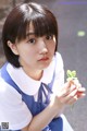 A young woman in a blue and white dress holding a green leaf.