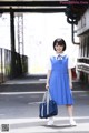 A woman in a blue dress is walking down the street.