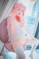 A woman with long pink hair sitting on a chair.