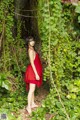 A woman in a red dress standing in the woods.