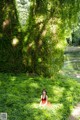 A woman in a red dress sitting under a tree.