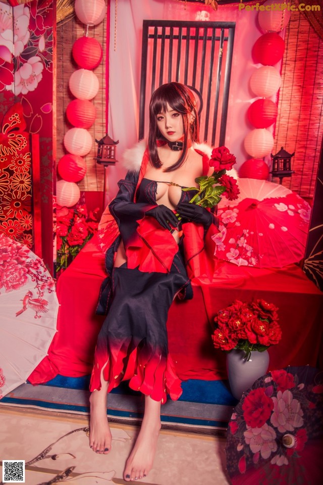 A woman in a red and black kimono sitting on a red couch.