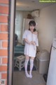 A woman standing in a kitchen next to a refrigerator.