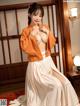 A woman in a white and orange kimono posing for the camera.