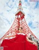 A woman in a red dress standing in front of the Tokyo Tower.