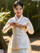 A woman in a white and yellow hanbok is posing for a picture.
