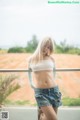 A woman in a white top and denim shorts posing for a picture.