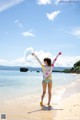 A woman standing on a beach with her arms outstretched.