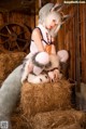 A woman sitting on top of a pile of hay.