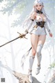 A woman with long white hair and pointed ears holds a sword, dressed in a white and gold outfit.