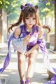 A woman in a purple and white outfit sitting on a bench.