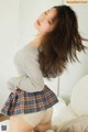 A woman in a plaid skirt is posing on a bed.