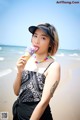 A woman eating an ice cream cone on the beach.