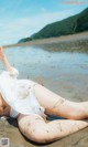 A woman laying on the beach covered in mud.