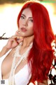 A woman with long red hair wearing a white dress.