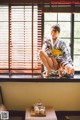 A woman in a kimono sitting on a window sill.