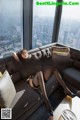 A woman sitting on a couch in front of a window.